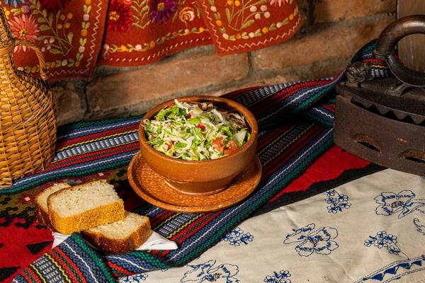 Sveža srpska salata u keramičkoj činiji uz hleb na tradicionalnom tekstilu